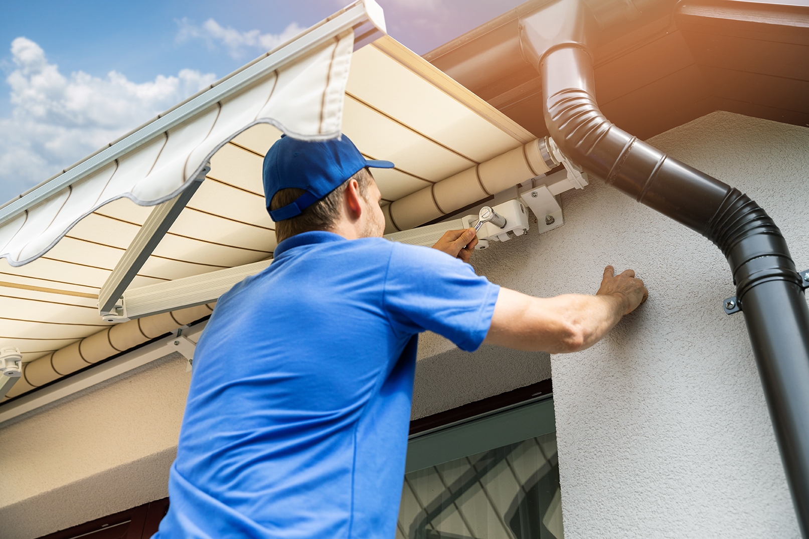 man installing awning on house facade wall over the balcony wind