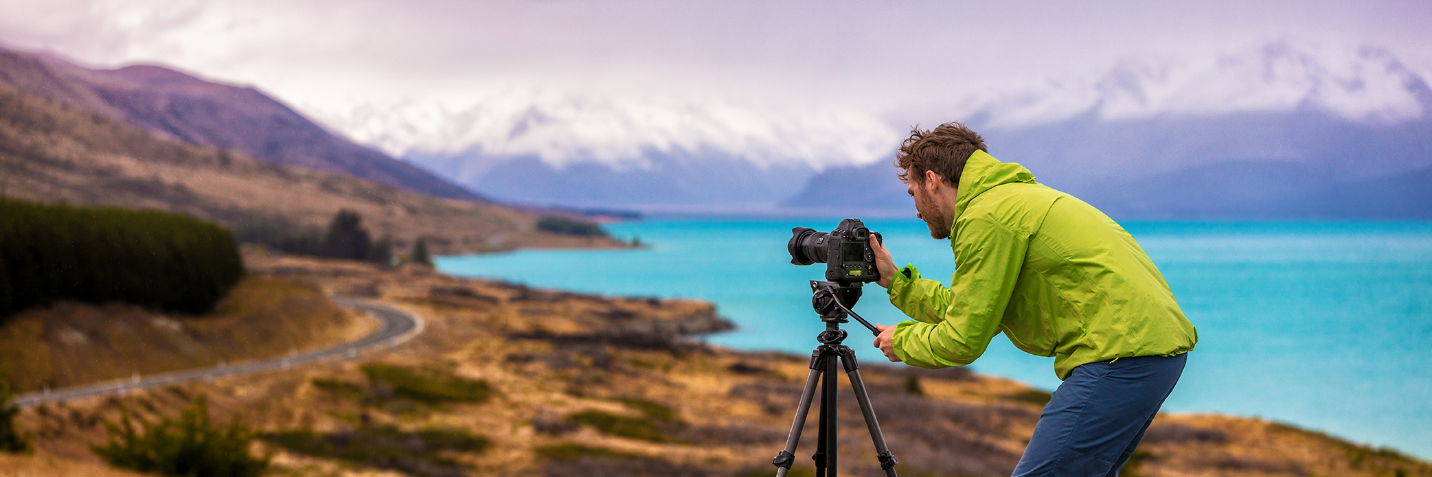 Travel photographer man taking nature video of mountain landscape at Peter's lookout, New Zealand Banner. Hiker tourist professional videographer on adventure vacation shooting slr camera on tripod.
